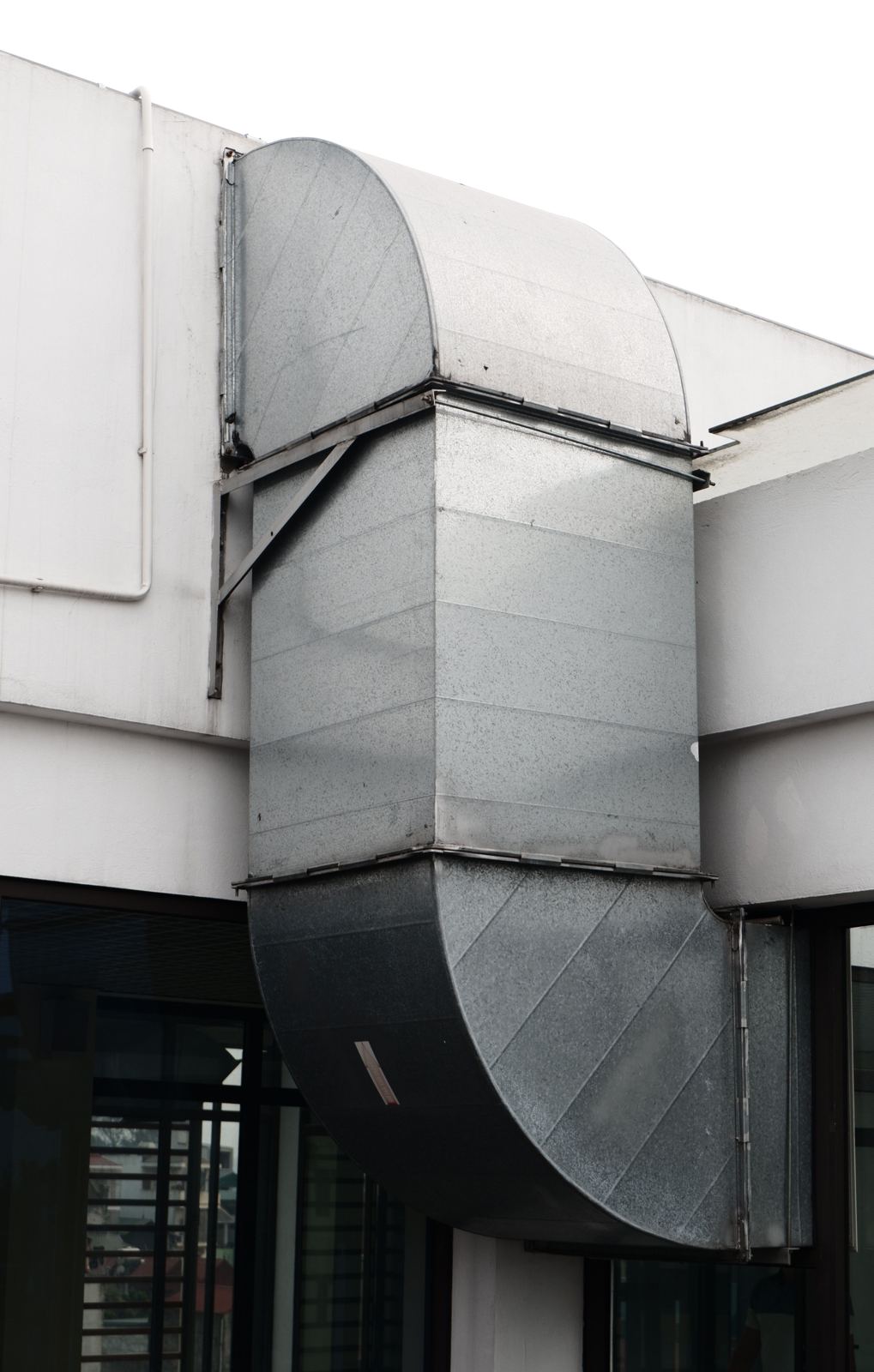 Galvanized rectangular ductwork with curved elbows mounted on a commercial building exterior