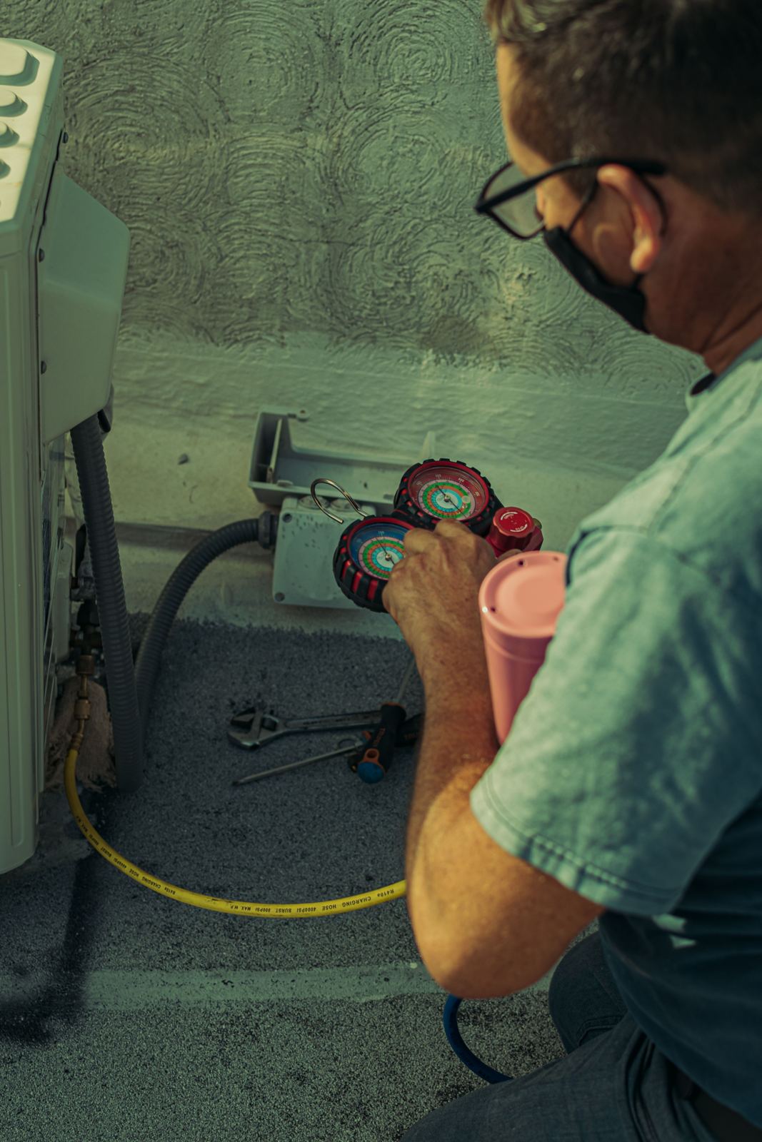 Technician checking refrigerant gauges on a heat pump outdoor unit