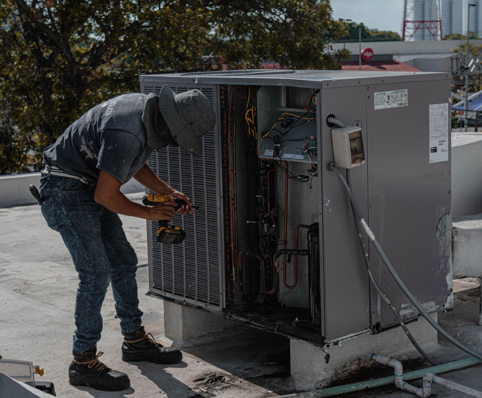 HVAC technician working on the cabinet of a rooftop unit during a system replacement