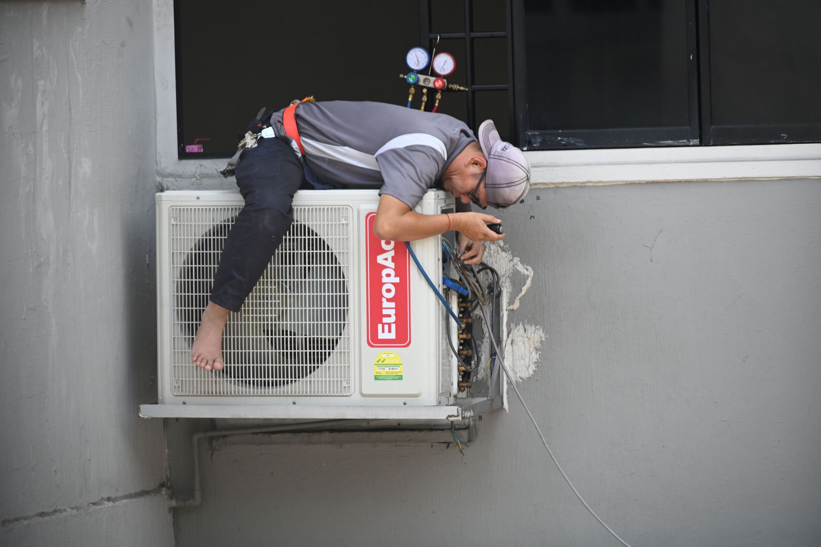 Installer connecting a ductless outdoor unit mounted on a wall bracket